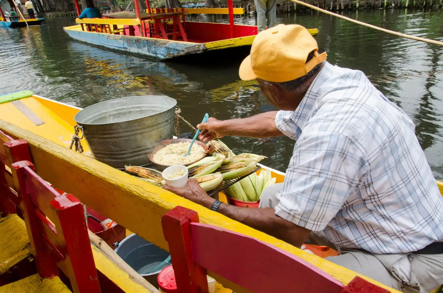 Man dishing out rice in colorful boat on water